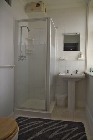A bathroom with a glass-enclosed shower, a sink, and a mirror above it. - The Anchorage (Weymouth)