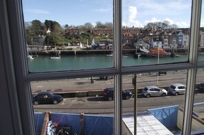 A view through a window of a harbor with boats, a dock, and buildings in the background. - The Anchorage (Weymouth)
