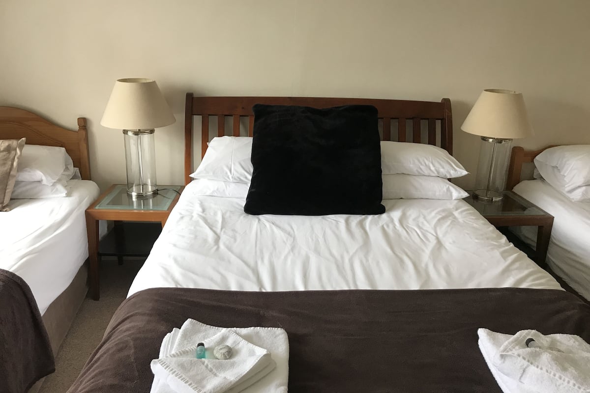 A hotel room with two single beds, a double bed, and two bedside lamps.
