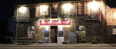 A building with a sign reading 'The Old Pound Inn,' featuring a brick facade, multiple windows, and outdoor seating.