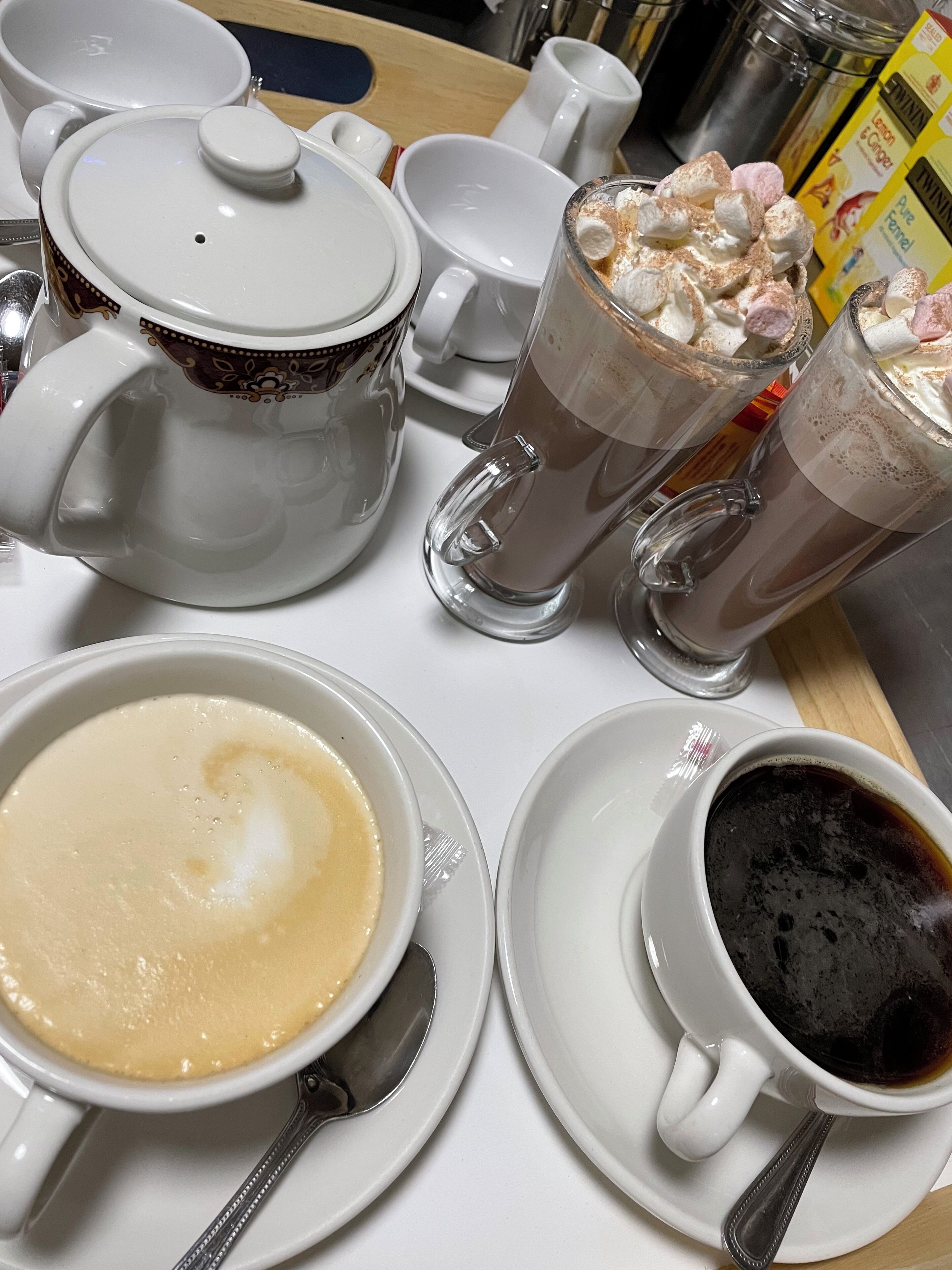 A table with various coffee and tea options, including a latte, espresso, and hot chocolate with marshmallows.