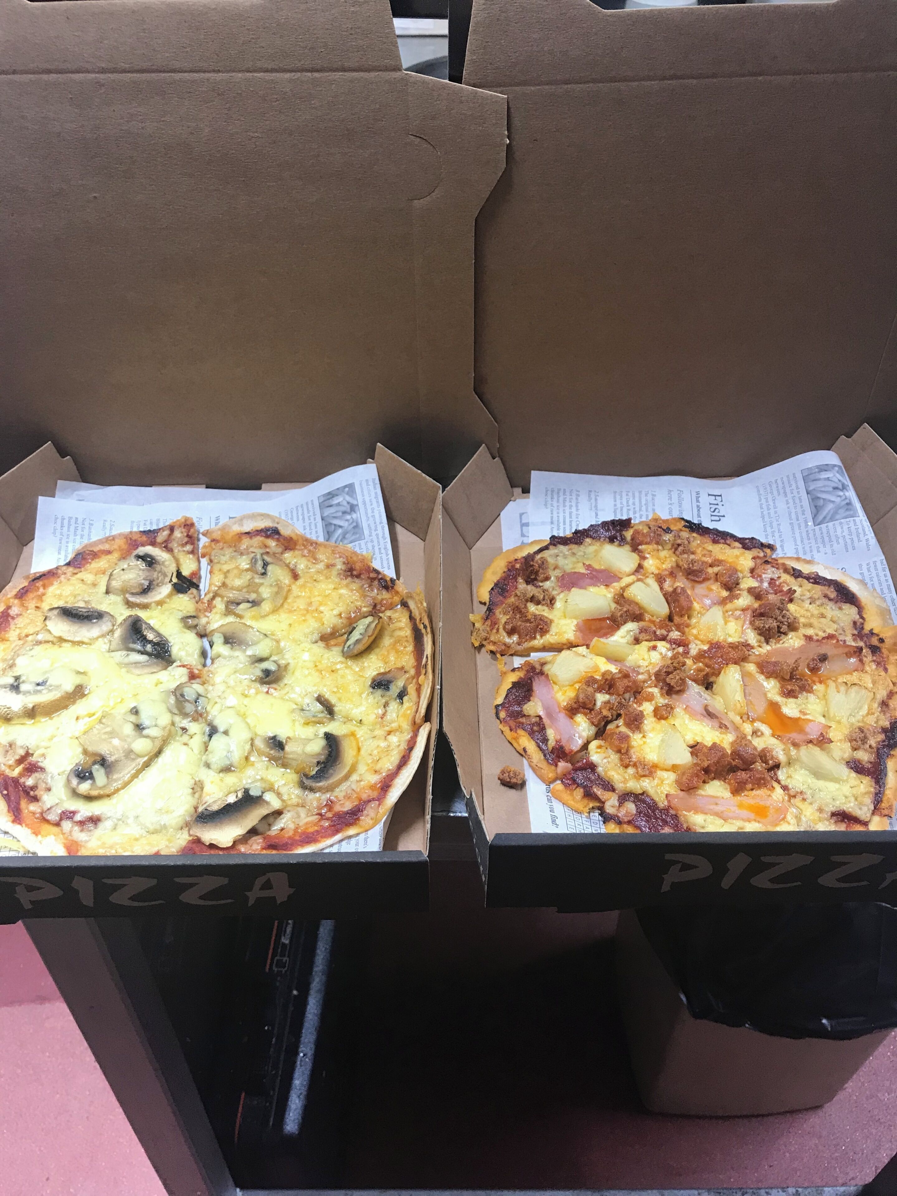 Two pizza boxes with different toppings, placed on a table.