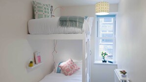 A bunk bed room with a window, a bedside table, and a hanging light fixture. - CellB - Hostel (Blaenau Ffestiniog)