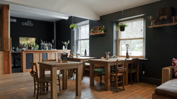 A cozy restaurant with wooden furniture, a bar area, and large windows. - CellB - Hostel (Blaenau Ffestiniog)