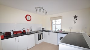 A modern kitchen with white cabinets, a microwave, a toaster, and a sink. - 3 Varis Apartments (Forres)