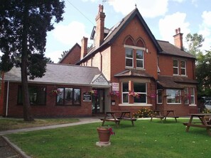 A two-story brick building with a reception area and a restaurant. There are picnic tables outside. - Heritage Hotel (Leicester)