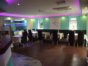 A restaurant with booths and tables, a bar area, and a large aquarium. - Heritage Hotel (Leicester)