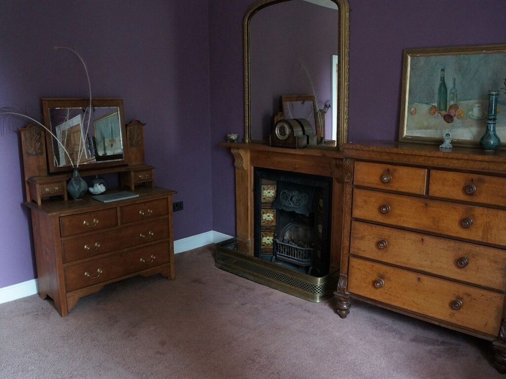 A room with a fireplace, wooden dresser, and a mirror.