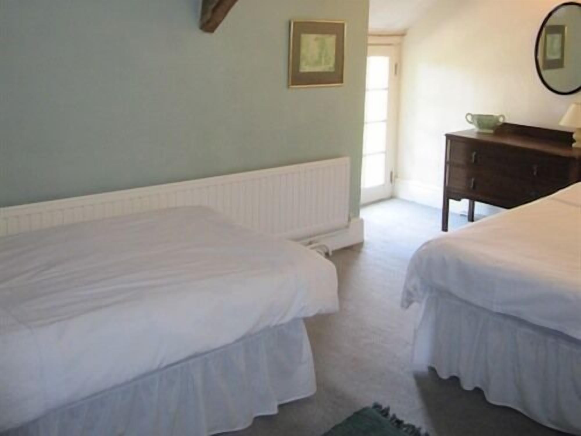 A bedroom with two single beds, a dresser, a mirror, and a framed picture on the wall.