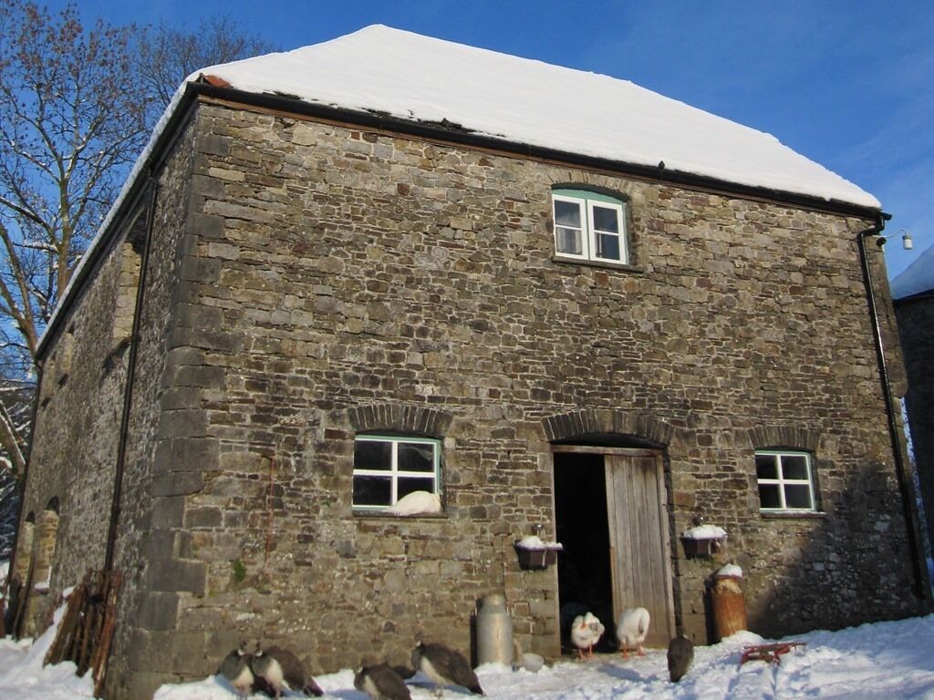 A stone building with a snow-covered roof and two windows.