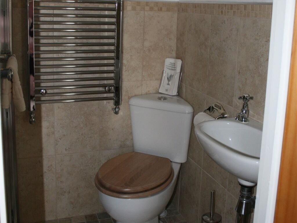 Un baño con inodoro, lavamanos y toallero.