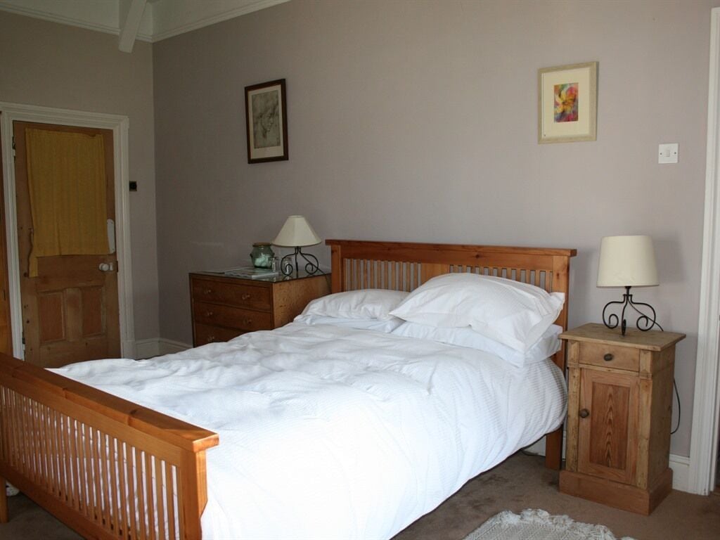 A bedroom with a wooden bed, bedside tables, and a door.