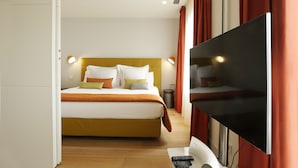 A modern hotel room with a bed, a flat-screen TV, and a desk with a laptop and remote controls. - Cosmo Apartments Rambla de Catalunya (Barcelona)