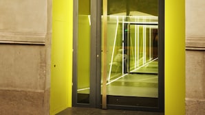 A building entrance with a glass door and a yellow wall. - Cosmo Apartments Rambla de Catalunya (Barcelona)