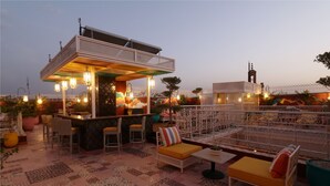Un área de estar al aire libre con bar, pisos de baldosas estampadas y una valla decorativa.