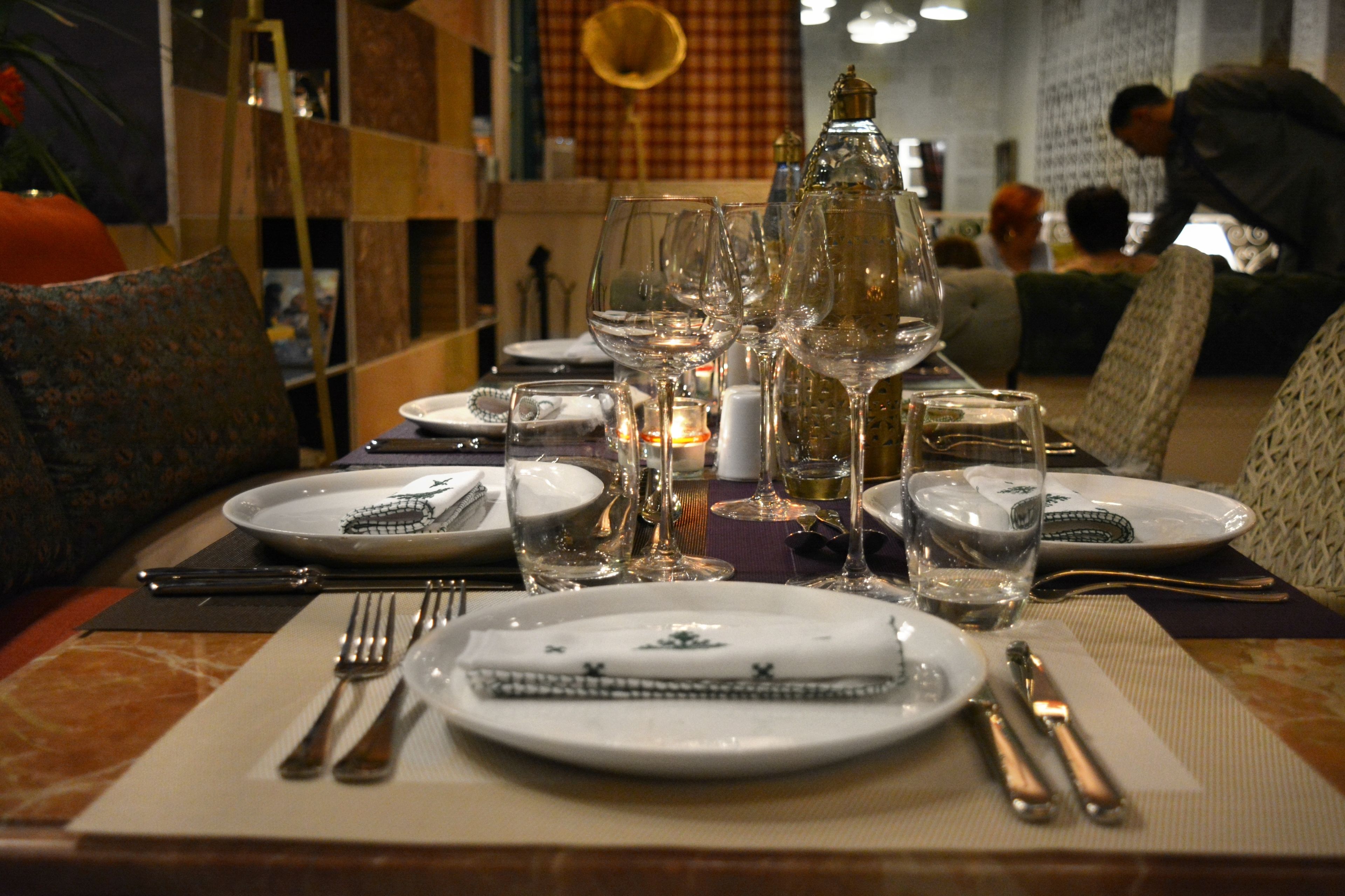 A dining table set with plates, glasses, and cutlery, with a candle and decorative items on the table.