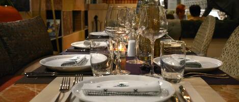 A dining table set with plates, glasses, and cutlery, with a candle and decorative items on the table.