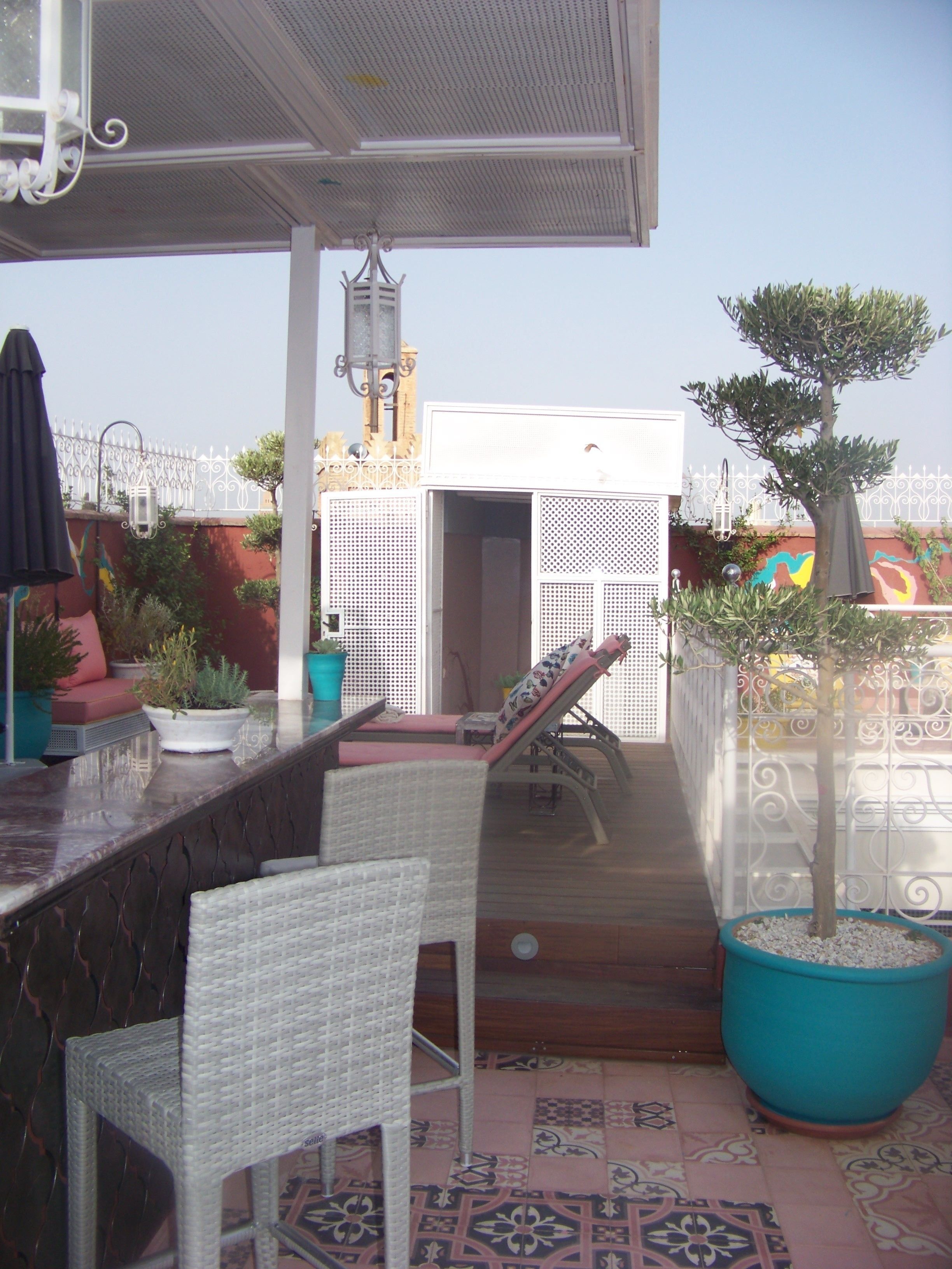 Un patio exterior con sillas de mimbre, una zona de bar y un árbol en maceta.