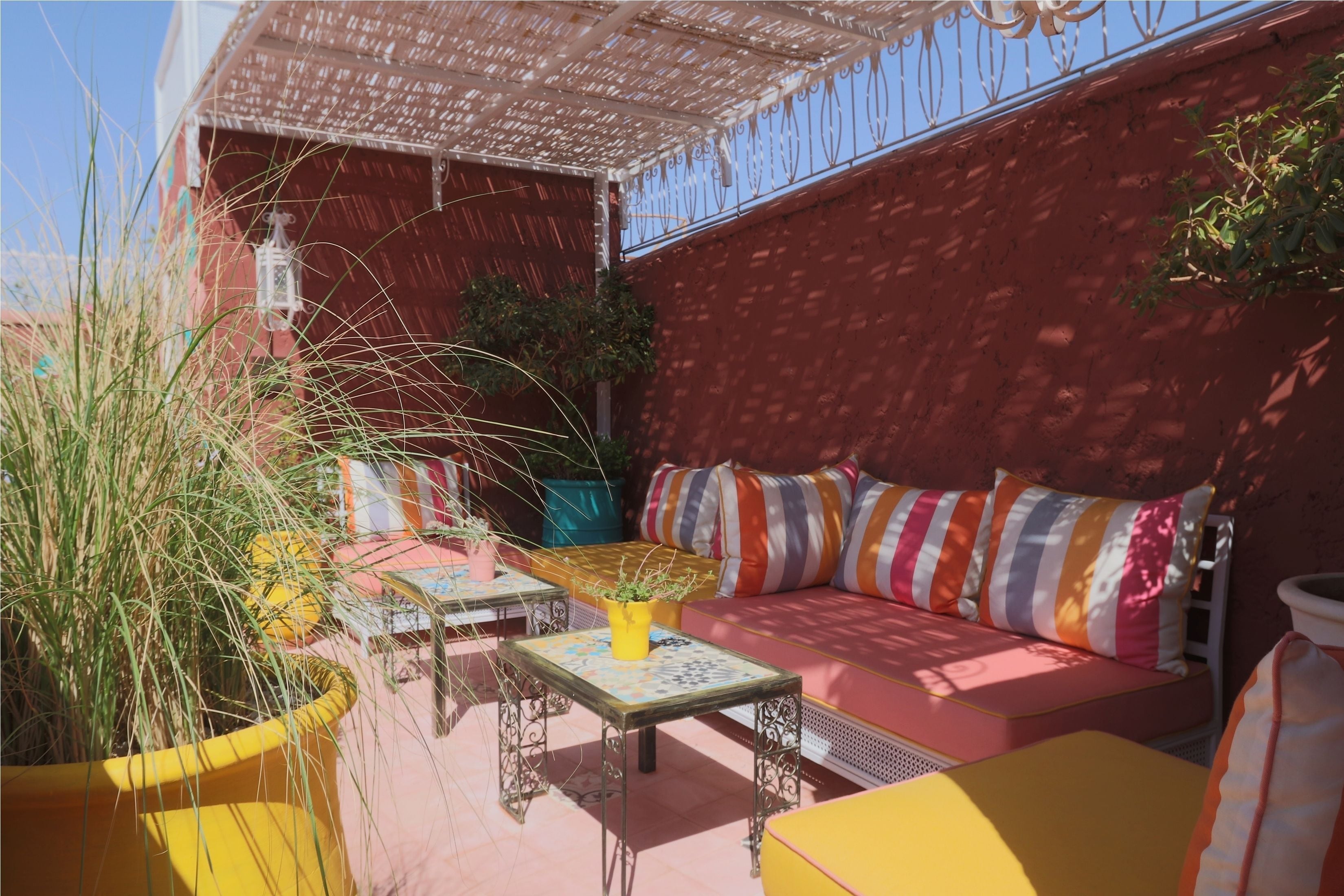 An outdoor seating area with a sofa, tables, and potted plants.