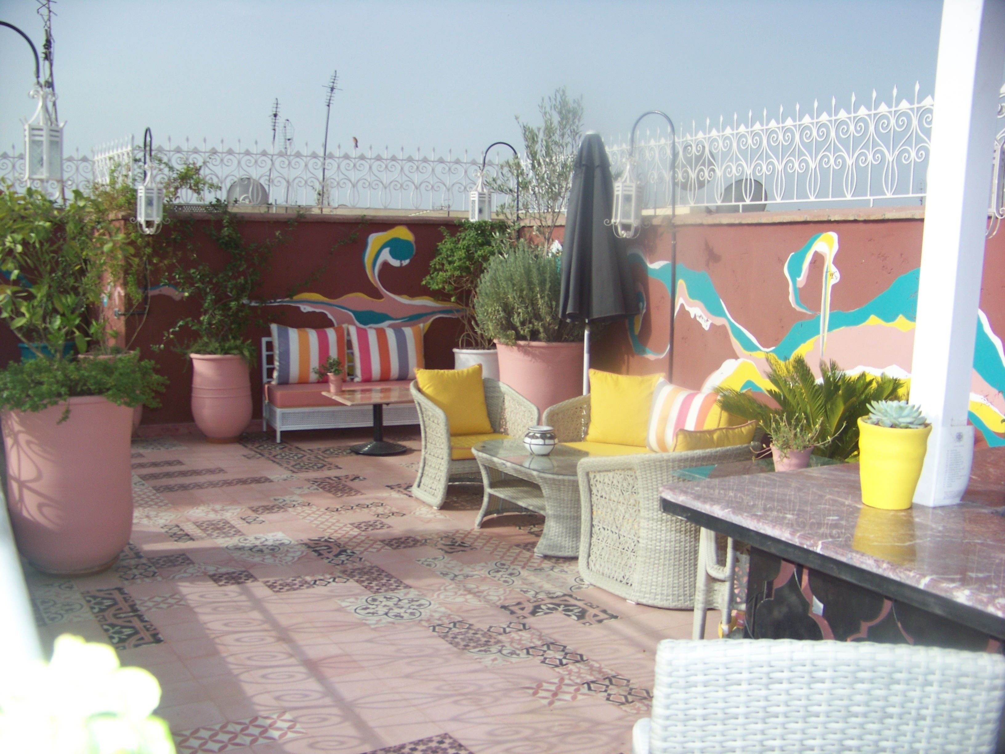 Une terrasse sur le toit, aménagée avec des espaces de détente en plein air, des plantes en pot et un mur décoratif.