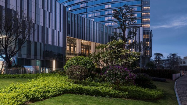 Un hôtel Hyatt Regency moderne, doté d’une façade en verre incurvée et d’un jardin bien entretenu à l’avant.