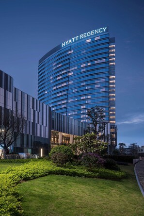 Un hôtel Hyatt Regency moderne, doté d’une façade en verre incurvée et d’un jardin bien entretenu à l’avant.