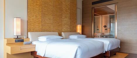 A modern hotel room with a large bed, wooden headboard, bedside tables, and a large mirror.