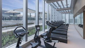 Une salle de sport équipée de tapis de course et d’appareils elliptiques, dotée de grandes fenêtres et offrant une vue sur l’extérieur.