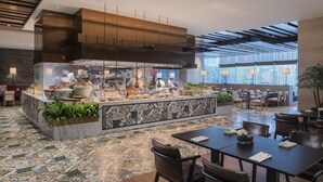 Un restaurant moderne doté d’un bar central, de différents espaces pour s’asseoir et d’un sol à motifs.