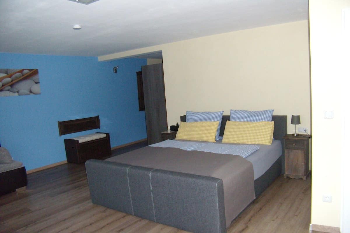 Un dormitorio con una cama grande, una mesita de noche y un pequeño rincón de descanso.