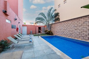 Una piscina al aire libre, sillones reclinables de piscina
