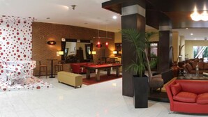 Eine geräumige Lobby mit einem Billardtisch, einem roten Sofa und einem modernen Kamin.