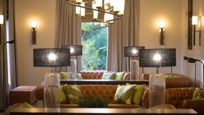 Ein helles Wohnzimmer mit großem Fenster, einer gepolsterten Couch und zwei Stehlampen.