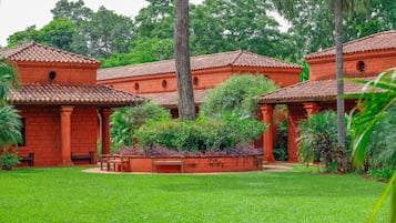 Ein Innenhof mit Gebäuden mit roten Dächern, umgeben von üppiger Vegetation und Palmen.