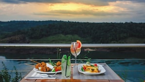 Ein Tisch mit Speisen und Getränken, mit Blick auf ein Gewässer und eine bewaldete Landschaft.
