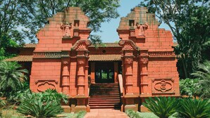 Ein roter Backstein-Tempel mit aufwendigen Schnitzereien und einer zentralen Treppe, die zu einem Eingang führt.