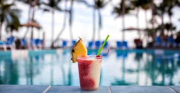 En drink med ananas og sugerør ved en pool.