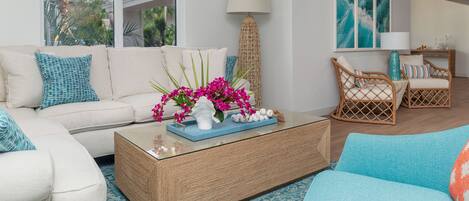 A living room with a sofa, coffee table, and wicker chairs.