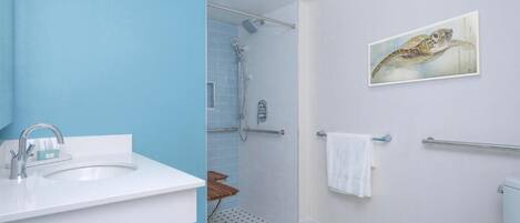 Une salle de bain avec un lavabo blanc, des murs bleus, une douche et des toilettes.
