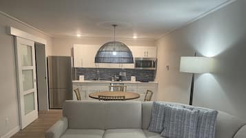 A modern living room with a sectional sofa, a wooden coffee table, and a dining area with a round table and chairs.