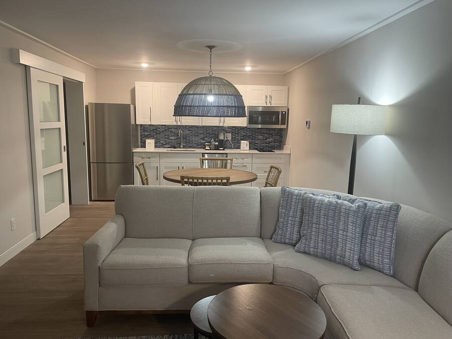 A modern living room with a sectional sofa, a wooden coffee table, and a dining area with a round table and chairs.