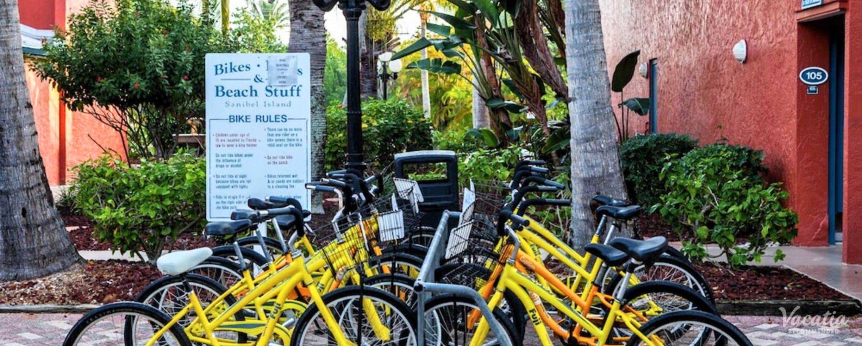 Una hilera de bicicletas amarillas estacionadas frente a un edificio con un cartel que enumera las normas para bicicletas.