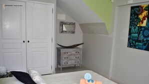 A bedroom with a bed, pillows, a dresser, a mirror, and a painting on the wall. - Cocokreyol - Grenadine (Trois-Ilets)