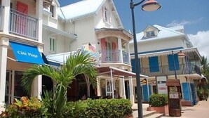 A building with a balcony, a sign that reads "Café Place," and a street lamp. - Cocokreyol - Grenadine (Trois-Ilets)