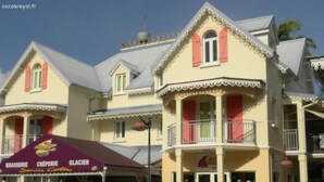 A building with a balcony, a sign for a restaurant, and a storefront. - Cocokreyol - Grenadine (Trois-Ilets)