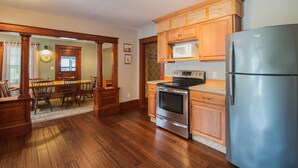 A kitchen with wooden cabinets, a stainless steel refrigerator, a microwave, and an oven. - Profile Motel & Cottages (Lincoln)