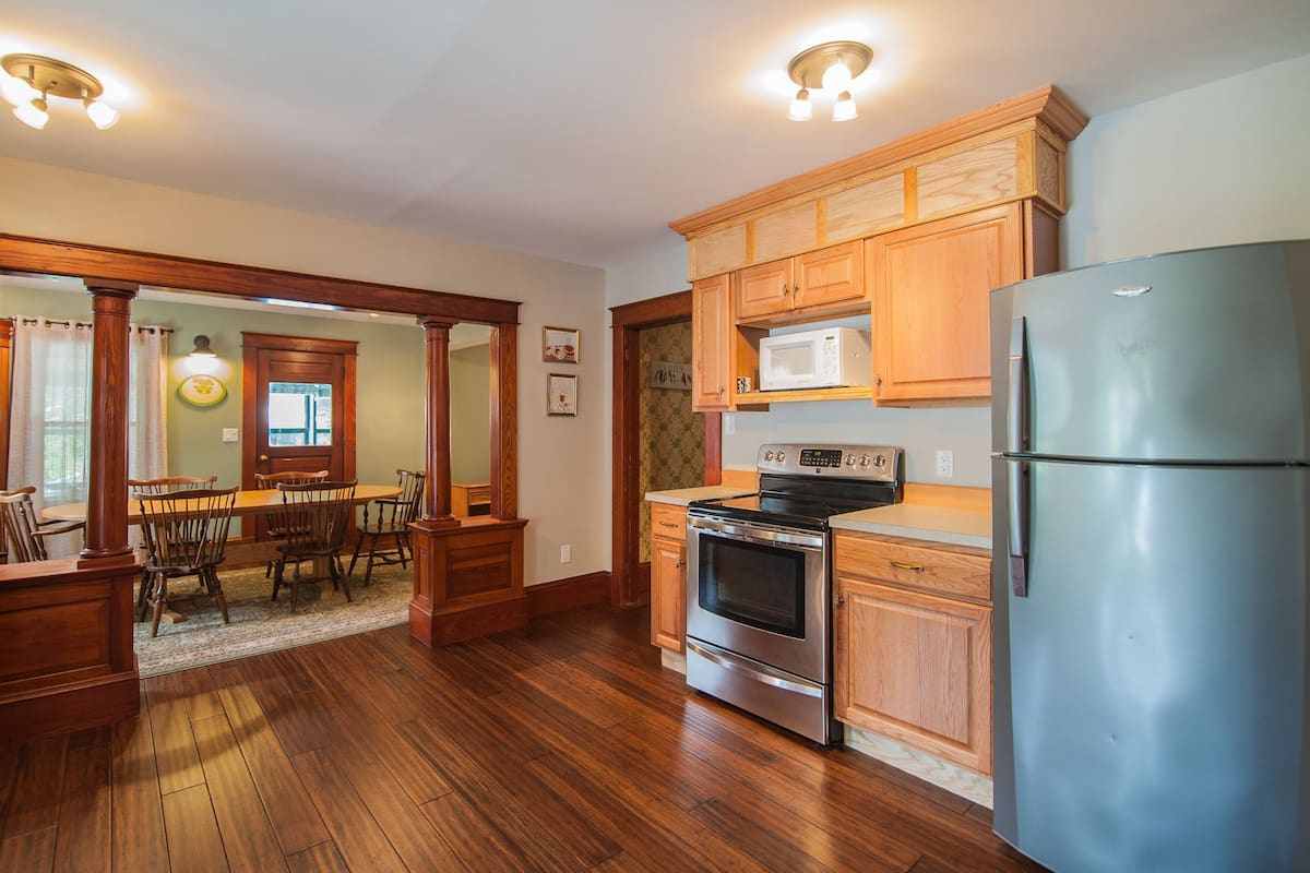 A kitchen with wooden cabinets, a stainless steel refrigerator, a microwave, and an oven.
