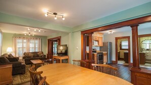 A spacious living room with a large wooden dining table, a comfortable sofa, and a television. - Profile Motel & Cottages (Lincoln)
