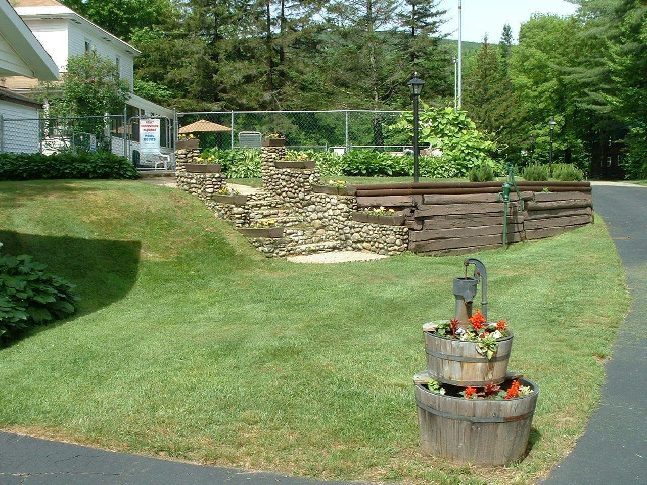 A well-maintained lawn with a stone retaining wall and a wooden planter with flowers.