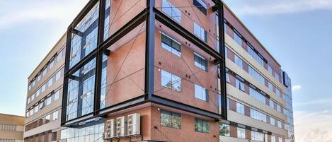 A multi-story building with a modern architectural design, featuring a combination of brick and glass facades, large windows, and a flat roof.